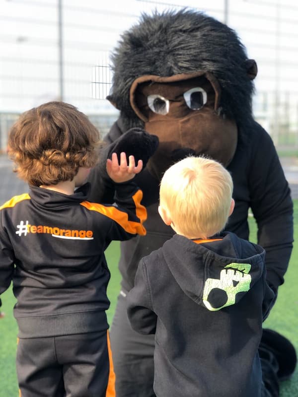 two kids at a Kixx childrens football franchise with the Kixx monkey mascot
