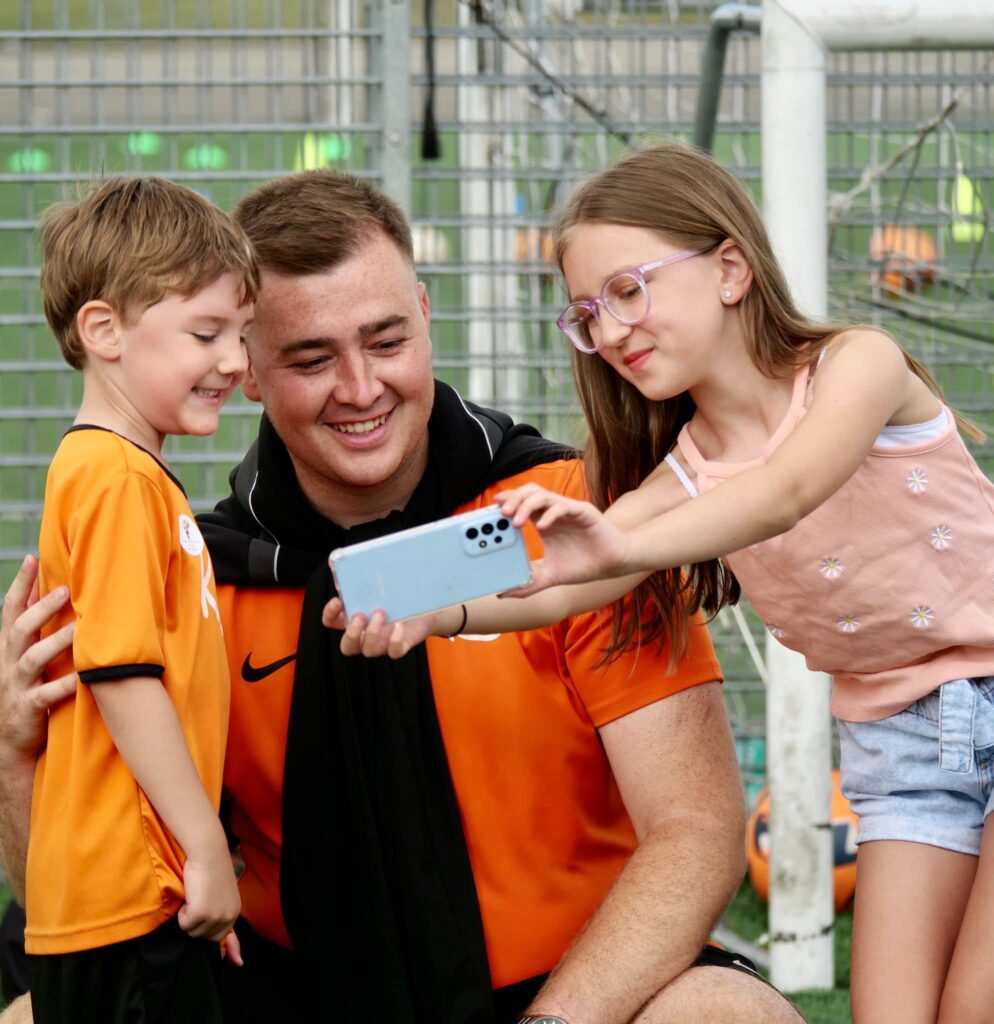 image of coach with two kids for blog Skills You Need to Thrive as a Children's Football Coach