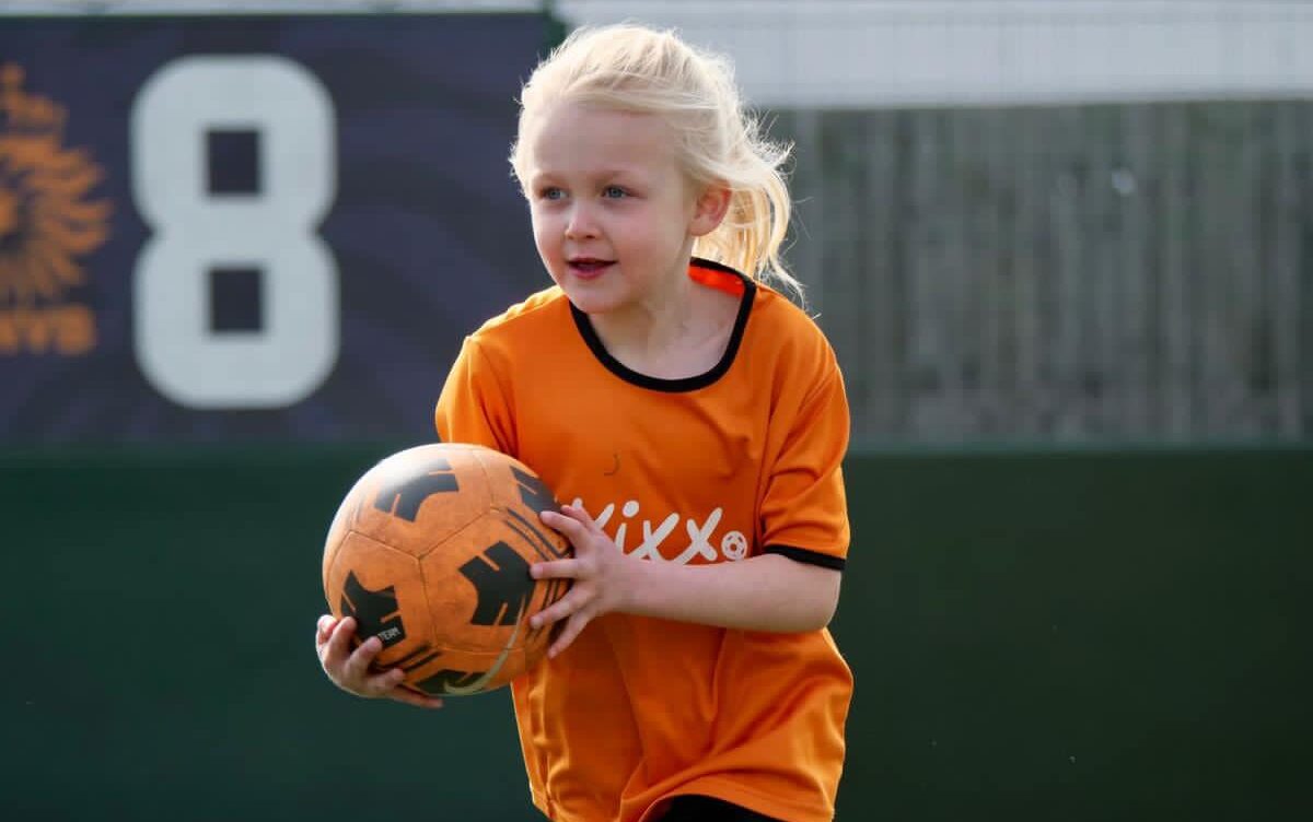 Image of girl playing football at Kixx football lessons for beginners