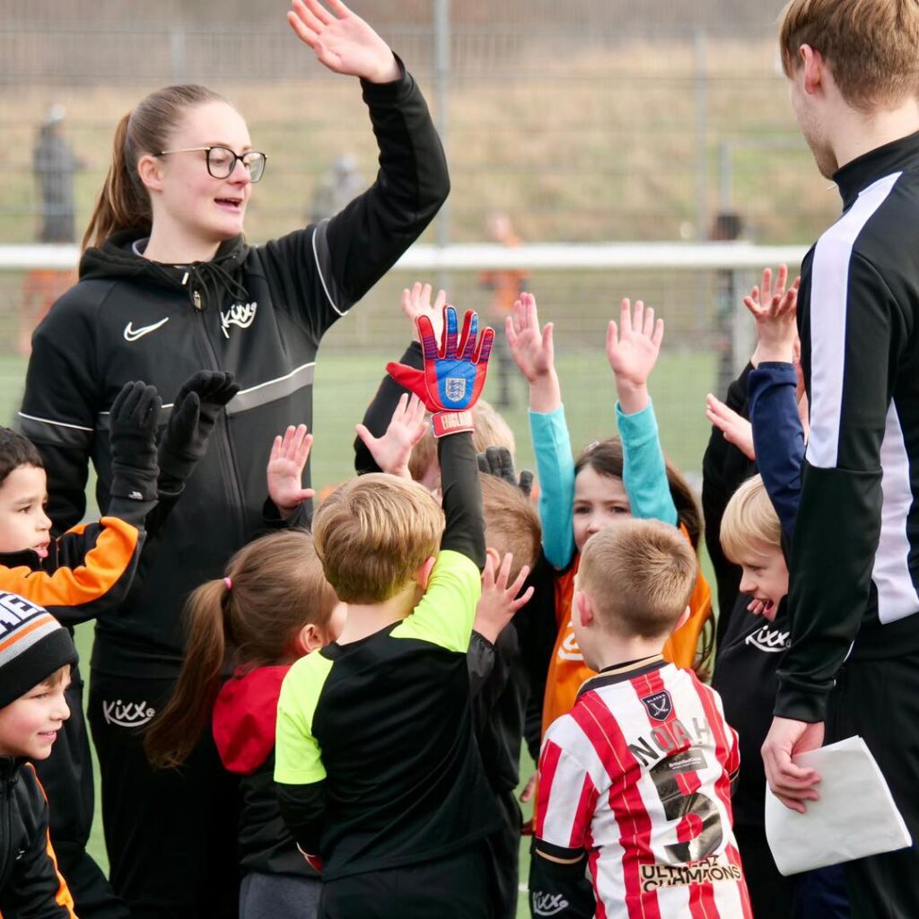 image of coach high fiving team for blog Why You Should Start Children's Football Classes In The Summer Holidays