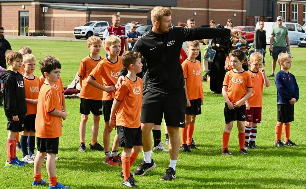 Image of a coach and franchisee owner directing a group of children in Kixx uniform for a blog called Starting Your Own Franchise: Investment, Support, and Success