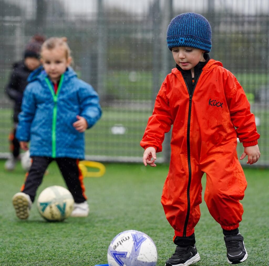 Image of a child in Kixx overalls playing football for the blog Exploring Benefits Beyond The Game 