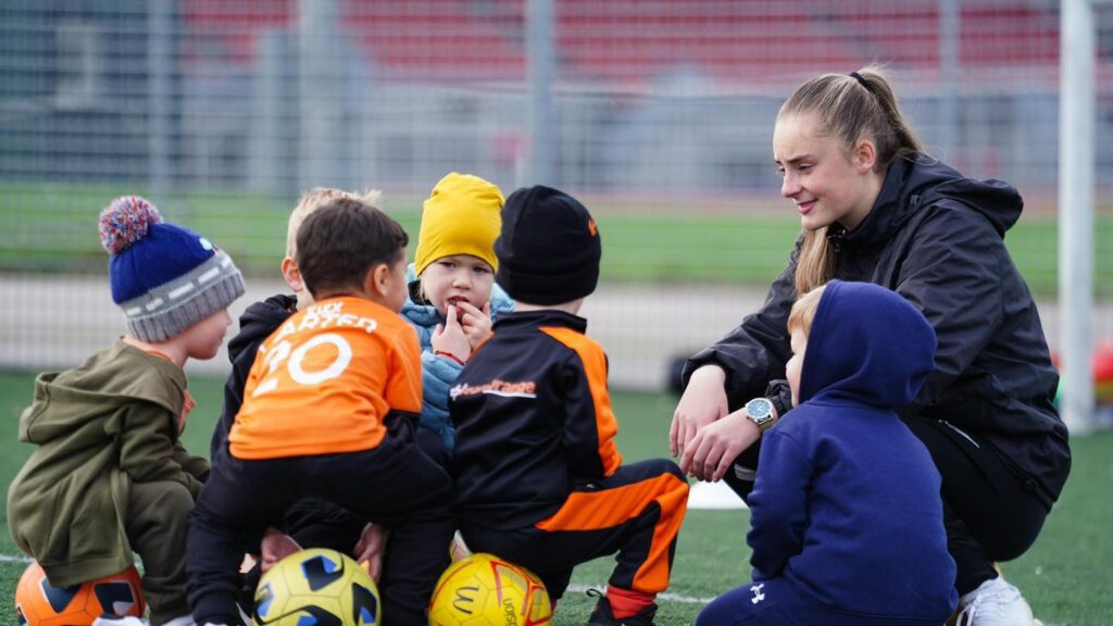 Image of a Kixx coach talking to some children at a session for the blog What Life Lessons Are Children Taught At Our Football Coaching Academy